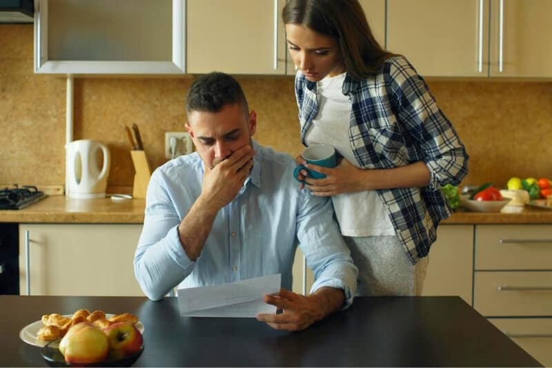 Worried couple reading a letter together at the kitchen table